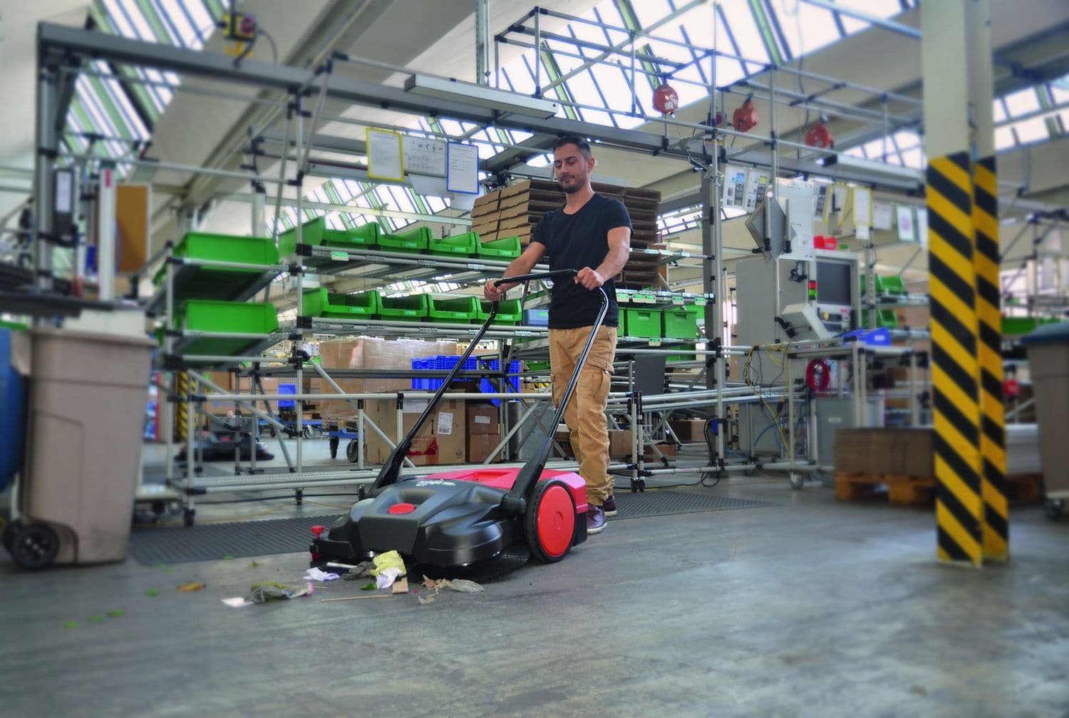 Mitarbeiter reinigt Industriehalle mit Kehrmaschine für Innen- und Außenbereiche