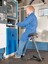 Mitarbeiter arbeitet im Stehen an einer Werkbank im Betrieb