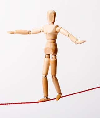 Holzfigur balanciert auf einer Linie als Symbol für den roten Faden in einer Präsentation